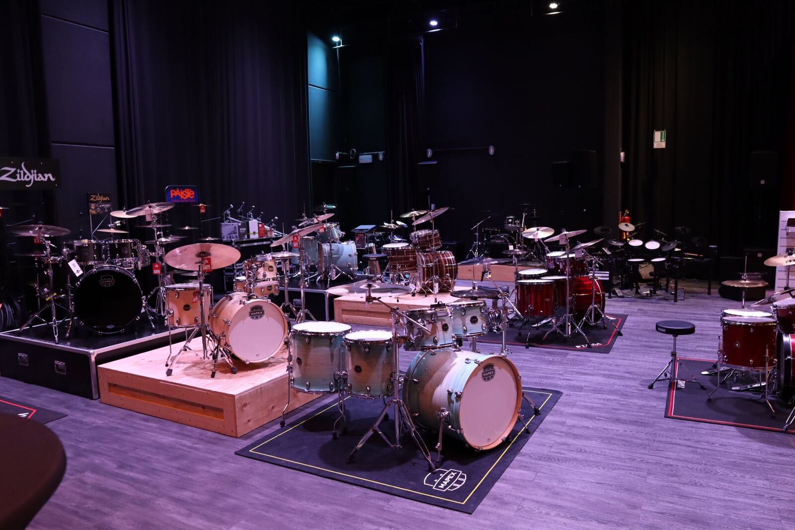 Grote zaal met drumstellen en podiumgordijnen