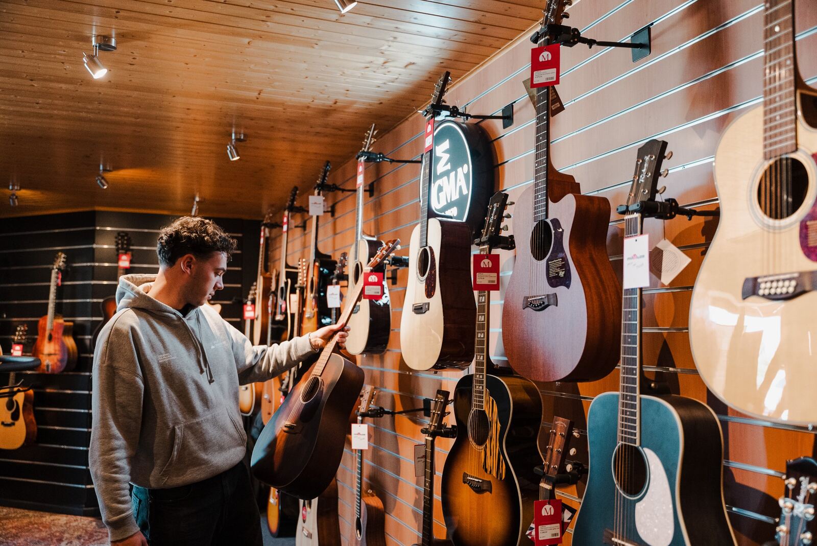 Klant bekijkt een akoestische gitaar aan de gitarenmuur